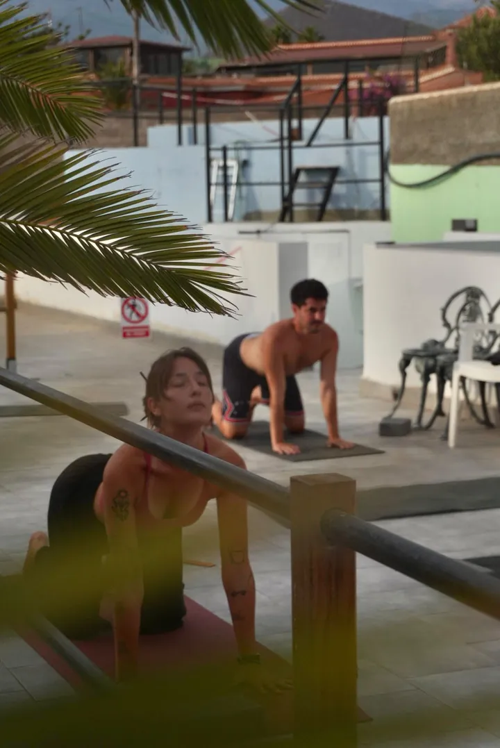 Nicole pratica yoga insieme a un allievo sulla terrazza